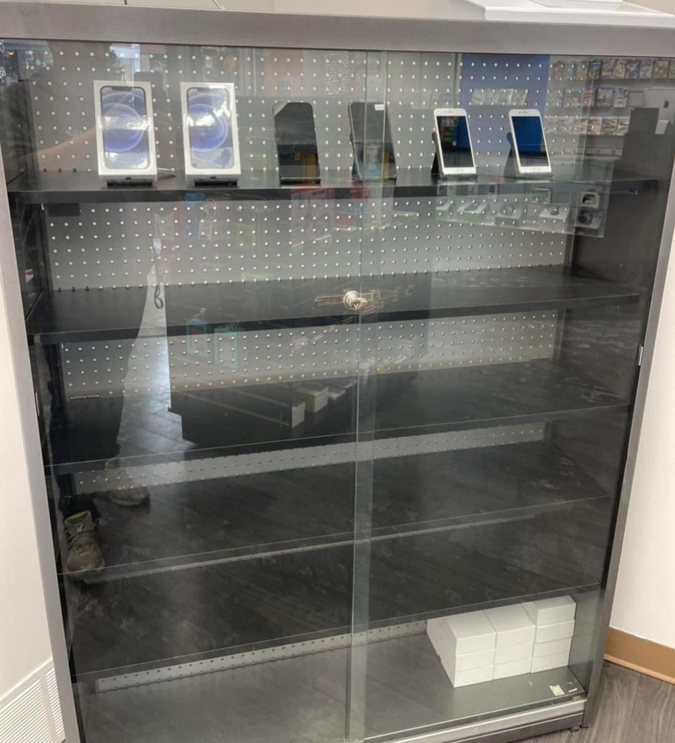 Display case with refurbished Apple devices and Beats headphones on shelves.