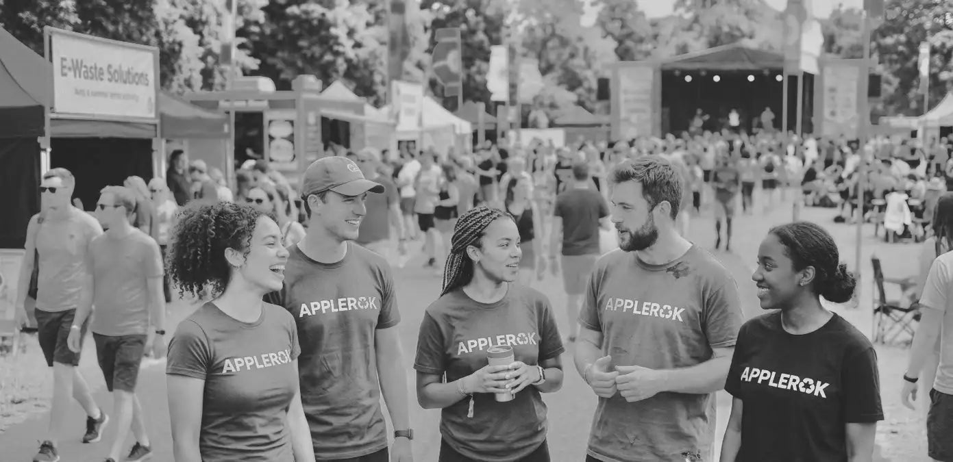 Group of people wearing matching shirts at an outdoor event with a stage in the background.