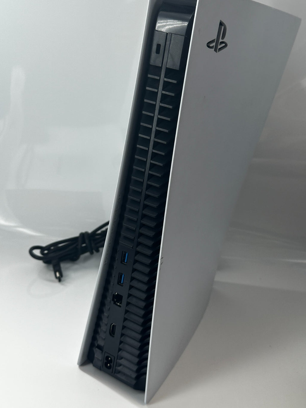 Angled white PlayStation 5 console showing black vents and rear ports.