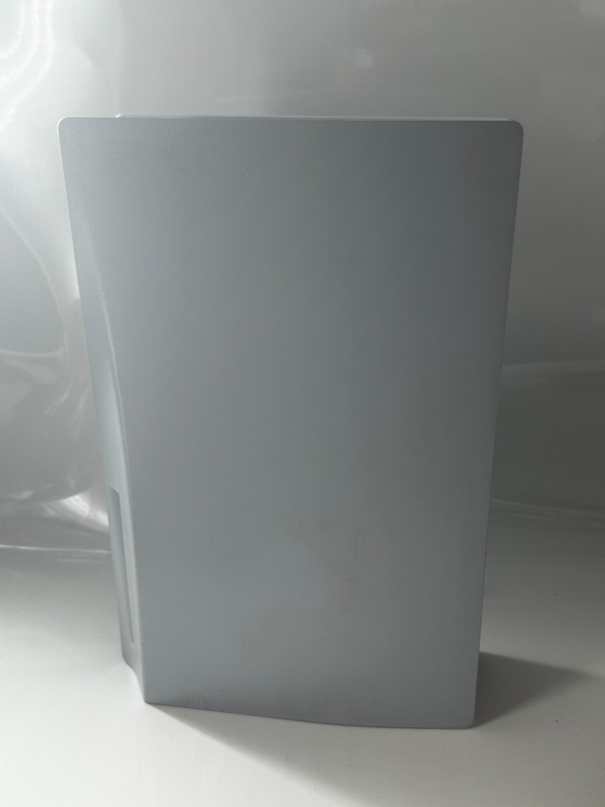 White curved side panel of a PlayStation 5 console standing upright.